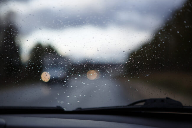 The Car Window Is Wet With Raindrops. Through The Windshield Vie