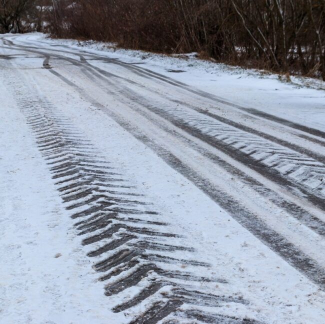 Tire Tracks On Icy Road Covered With Snow
