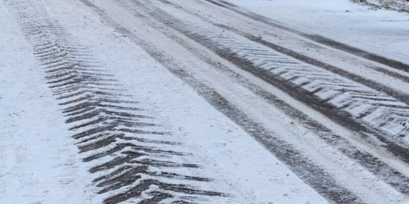 Tire Tracks On Icy Road Covered With Snow