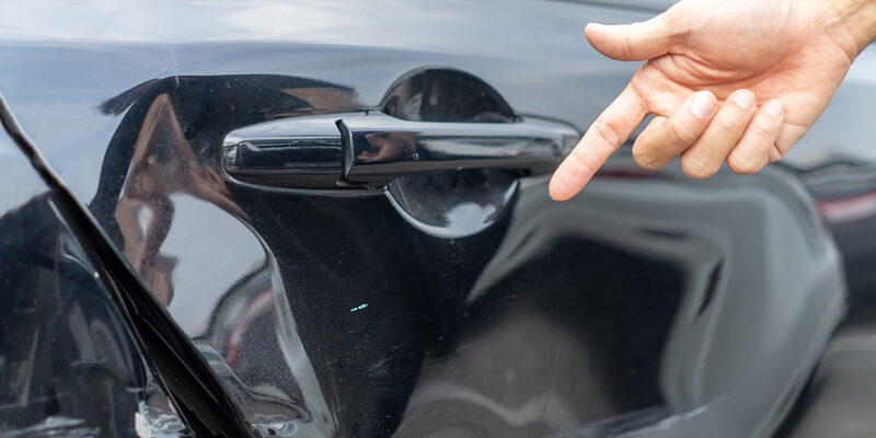 Man Hand Pointing On Car Bumper Dented Broken On Black Car Door.