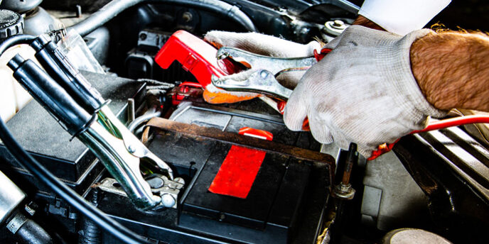 Attaching Clips To A Car Battery Under A Hood, At Night. Jump St